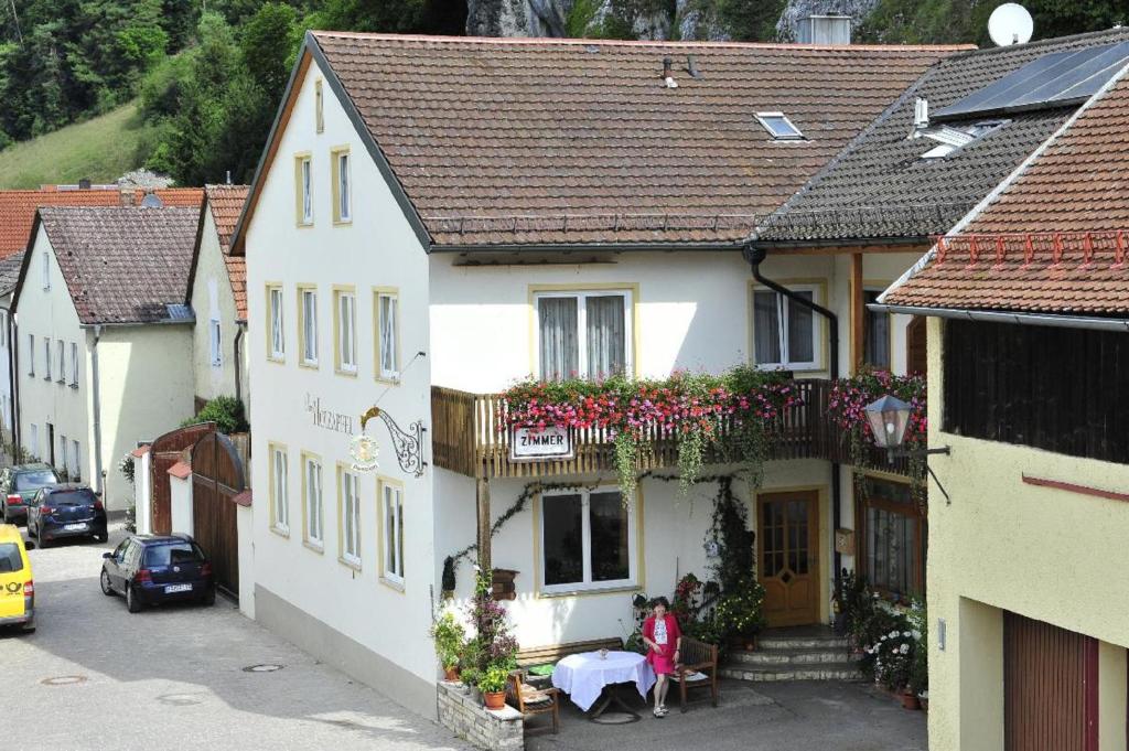 a woman sitting at a table in front of a building at Pension Holzapfel in Essing