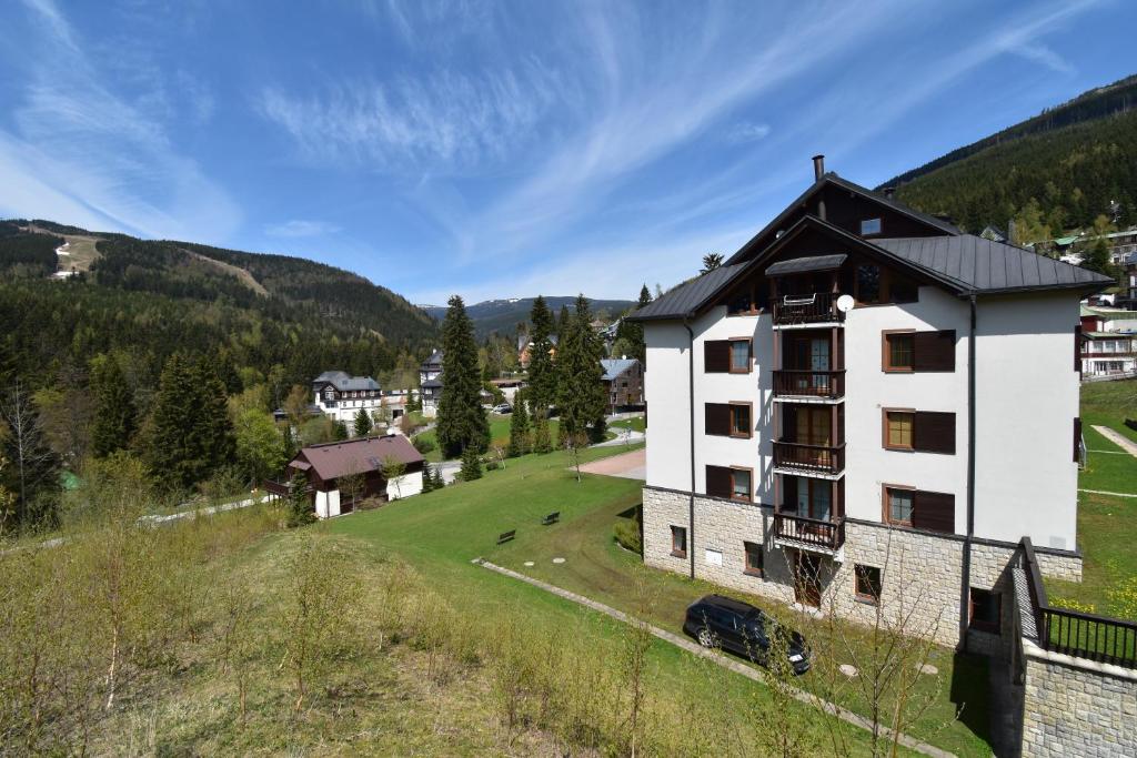 un edificio blanco con techo negro en un campo verde en Apartment Dalibor II. en Špindlerův Mlýn