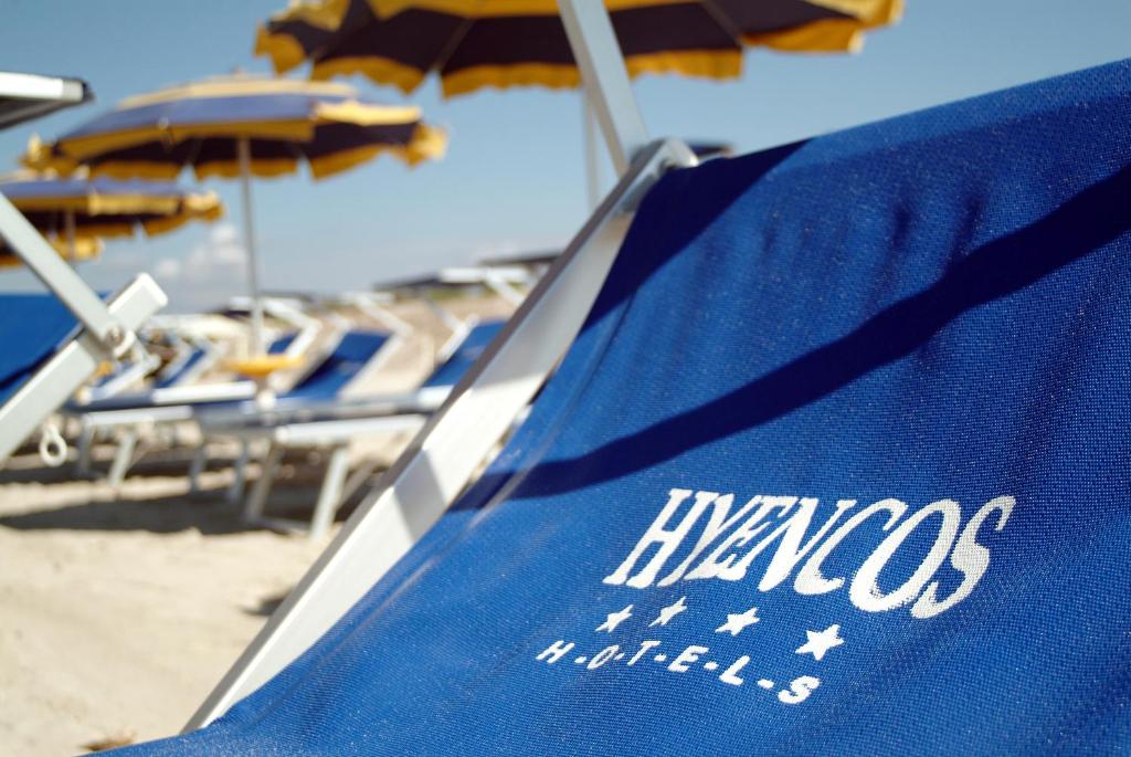 un asciugamano blu sulla spiaggia con sedie e ombrelloni di Hyencos Hotel Calos a Torre San Giovanni Ugento