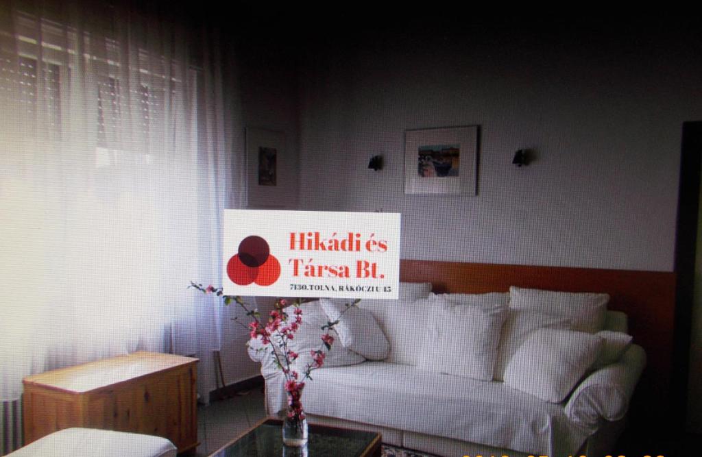ein Wohnzimmer mit einer weißen Couch und einem Schild in der Unterkunft Thelena Apartman in Tolna