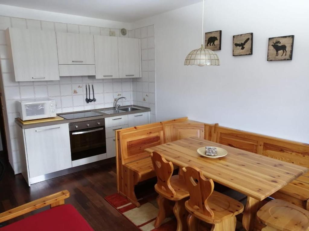 eine Küche mit weißen Schränken und einem Holztisch in der Unterkunft Plodn House in Sappada