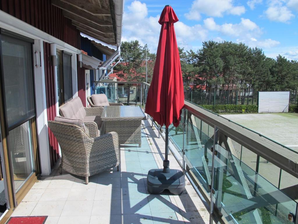 un patio con sillas y una sombrilla en el balcón en Nida Vėtrungių 3, Marių apartamentai, en Nida