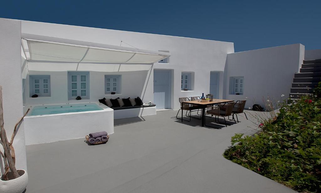 a white patio with a table and a pool at Anemolia Villa in Megalochori