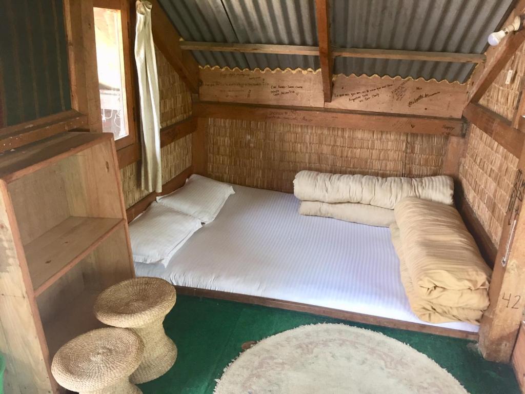 a small room with two beds and two stools at Hotel At The End Of The Universe in Nagarkot