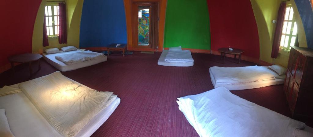 a room with three beds and two windows at Hotel At The End Of The Universe in Nagarkot