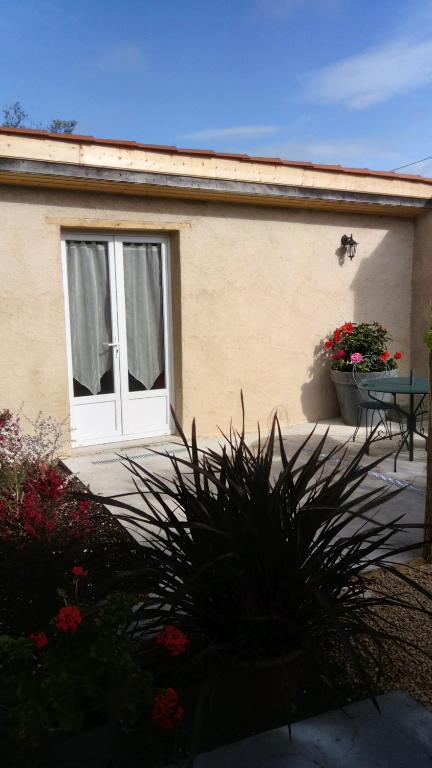 a house with a table and a window and flowers at l'orchidée in Talais
