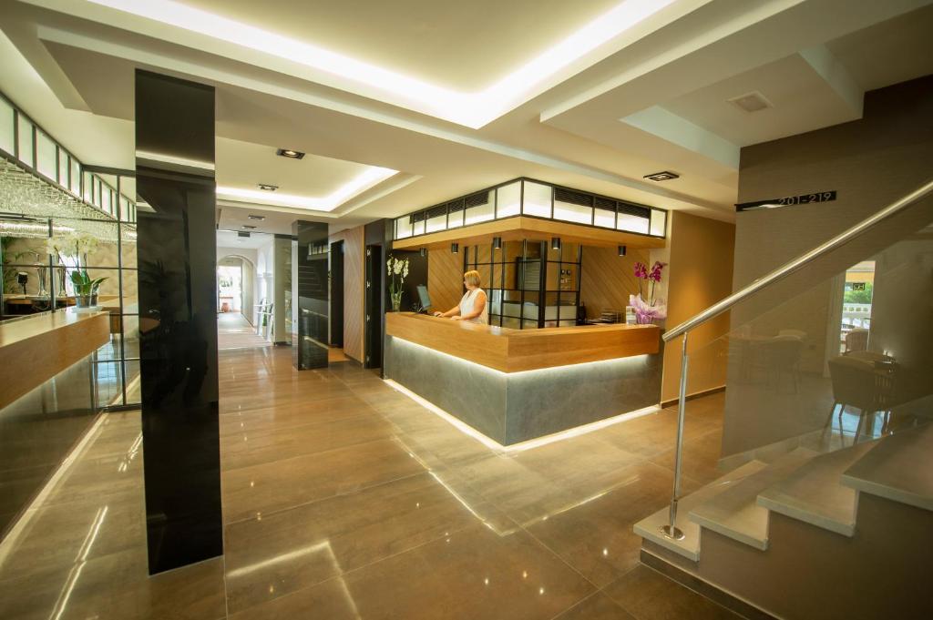 a lobby with a woman sitting at a counter at Hotel Diufain in Conil de la Frontera