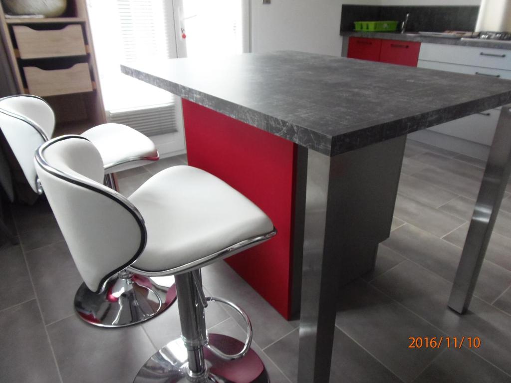 a kitchen with a red island with four white bar stools at mini villa studio que du bonheur in Calenzana