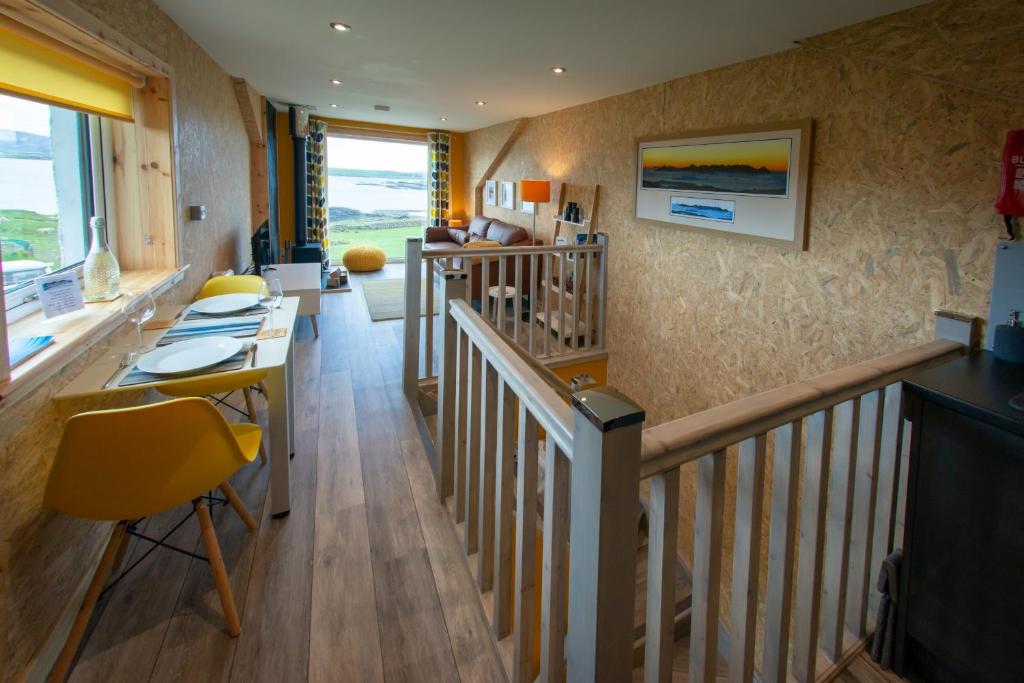 a room with a staircase with a table and yellow chairs at Lochanside in Struan