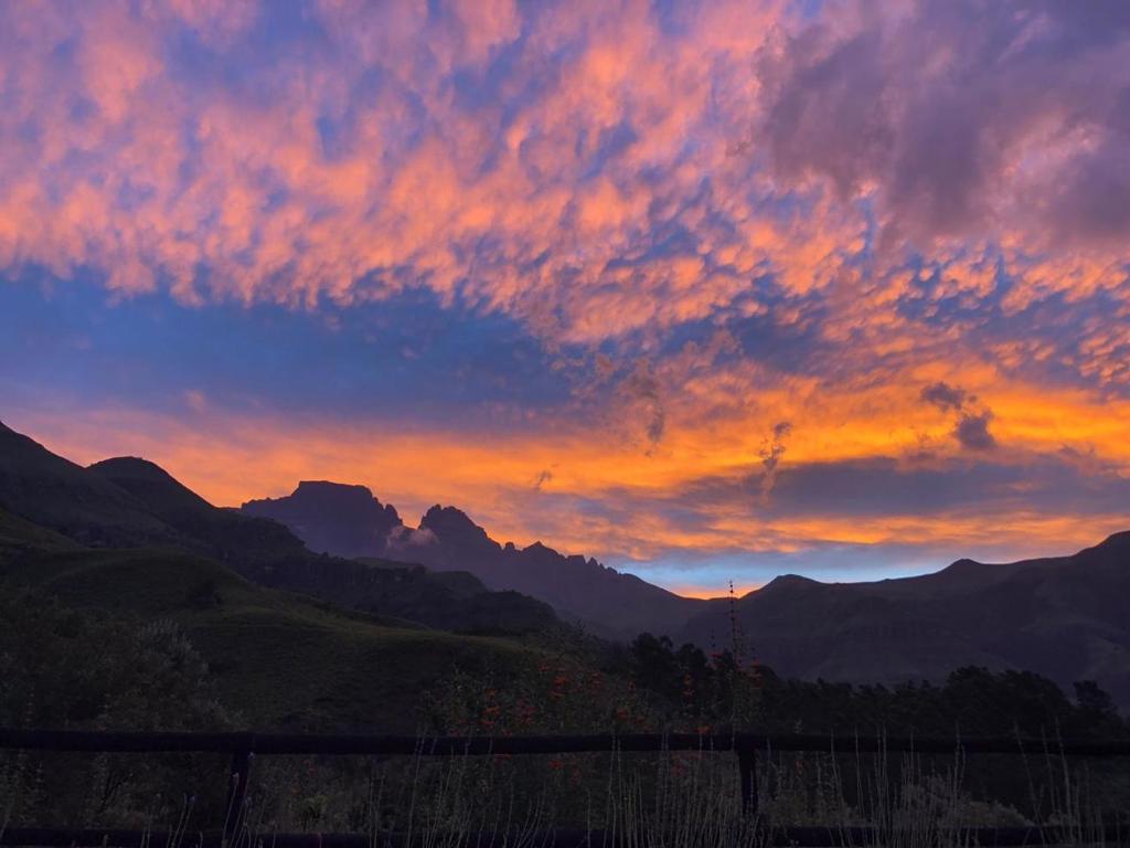 a sunset in the mountains with a fence in the foreground at Highbourne Cottages in Winterton