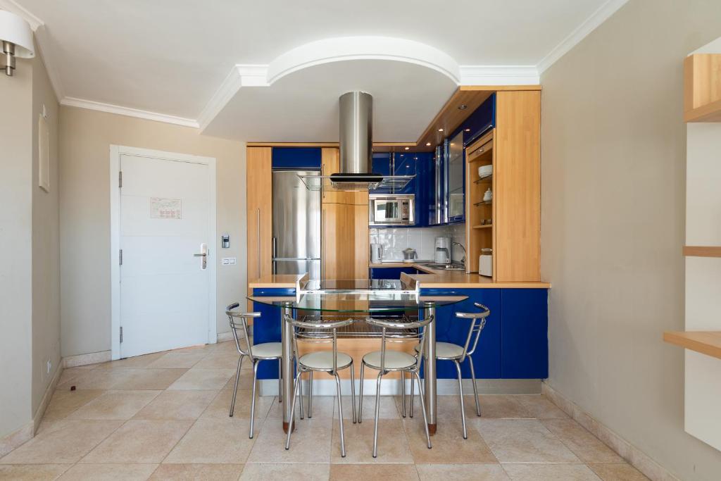 a kitchen with blue cabinets and a glass table at Holiday Club Vista Amadores in Amadores