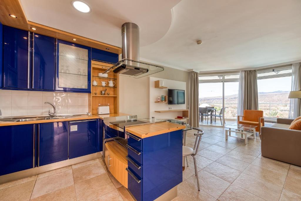 a kitchen with blue cabinets and a living room at Holiday Club Vista Amadores in Amadores