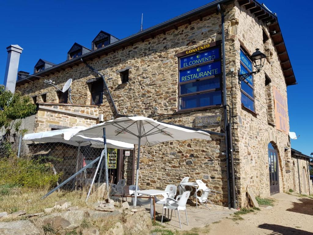 un edificio con una mesa y una sombrilla delante de él en Convento de Foncebadon en Foncebadón