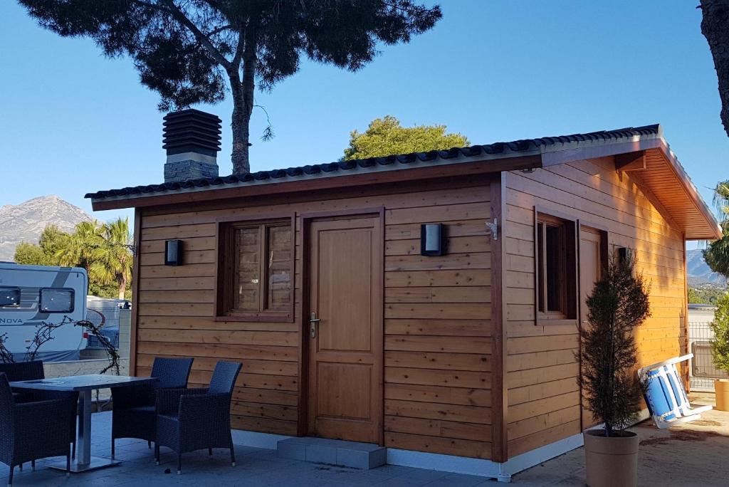 um pequeno chalé de madeira com uma mesa e cadeiras em Camping La Colina em Albir