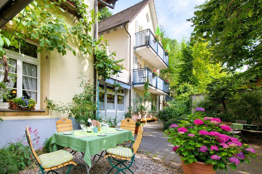 um pátio com uma mesa, cadeiras e flores em Hotel-Bio Gasthaus Am Felsenkeller em Staufen