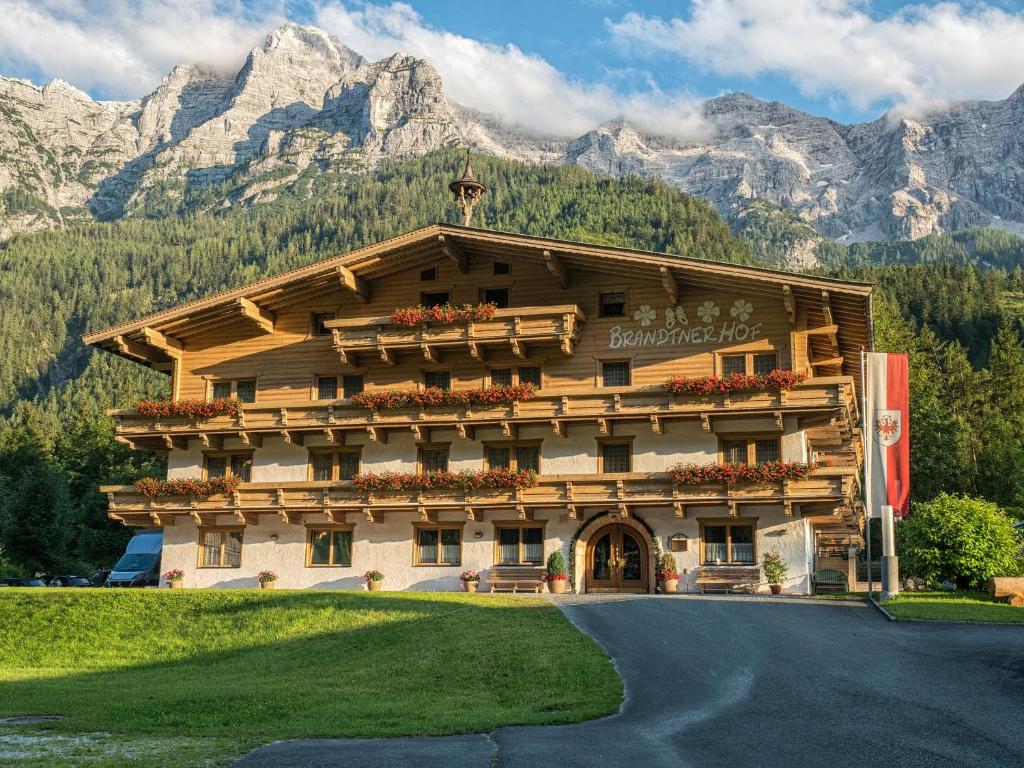 a large building with flowers in front of a mountain at Brandtnerhof Betriebe in Waidring