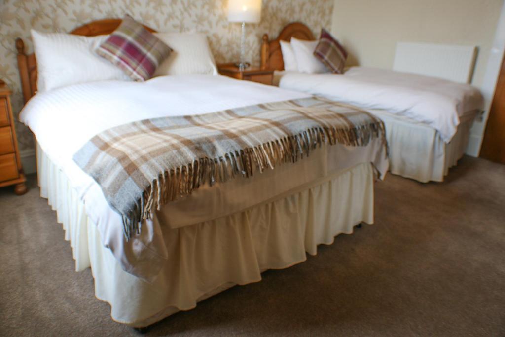 two beds in a hotel room with white sheets at Station Hotel Stonehaven in Stonehaven