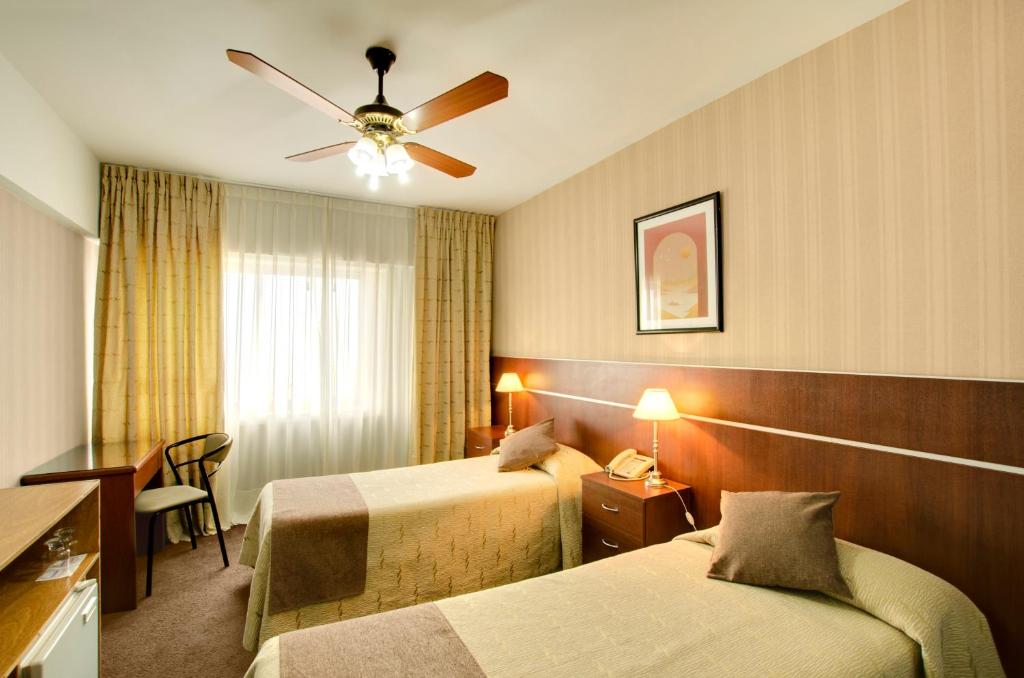 a hotel room with two beds and a ceiling fan at Hotel 13 de Julio in Mar del Plata