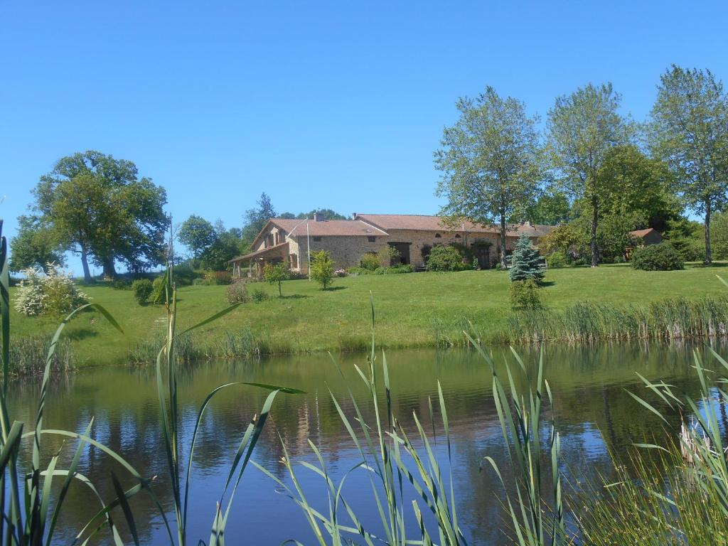 une maison sur une colline à côté d'un lac dans l'établissement chambres d'hotes les quatre vents, à Bussière-Galant
