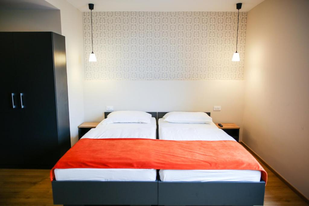 a bedroom with two beds and two lights at Ambient Hotel in Domžale