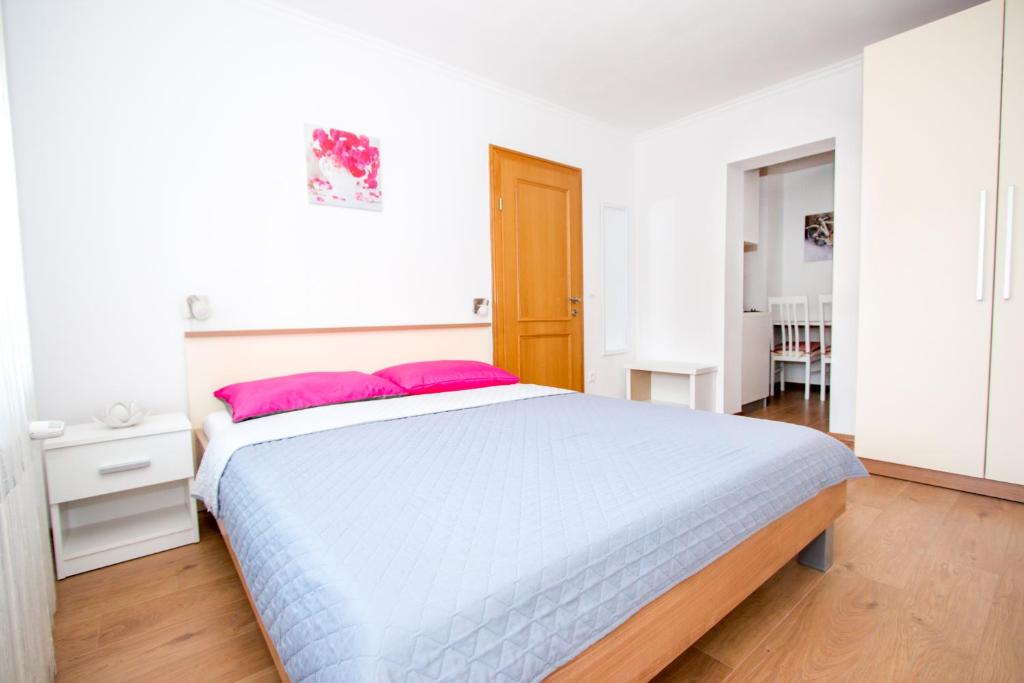 a white bedroom with a large bed with pink pillows at NADA in Karlovac
