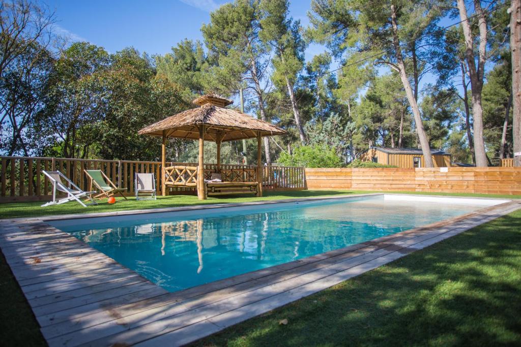 a swimming pool with a gazebo next to a yard at Camping du Garlaban in Aubagne