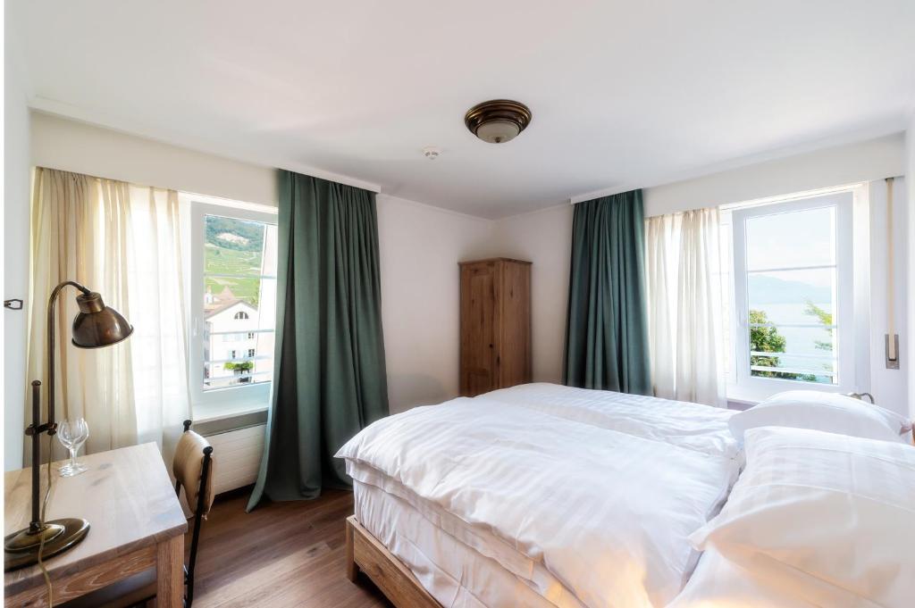 a bedroom with a large bed and two windows at Au Major Davel in Cully
