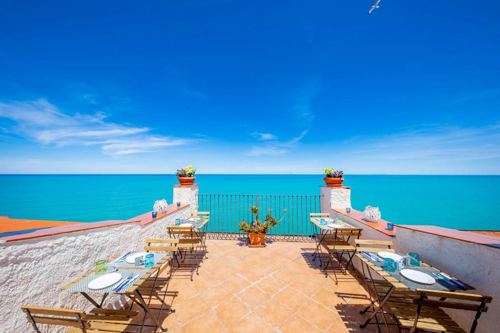 a patio with tables and chairs overlooking the ocean at Casanova Rooms and Apartment to Rent in Cefalù