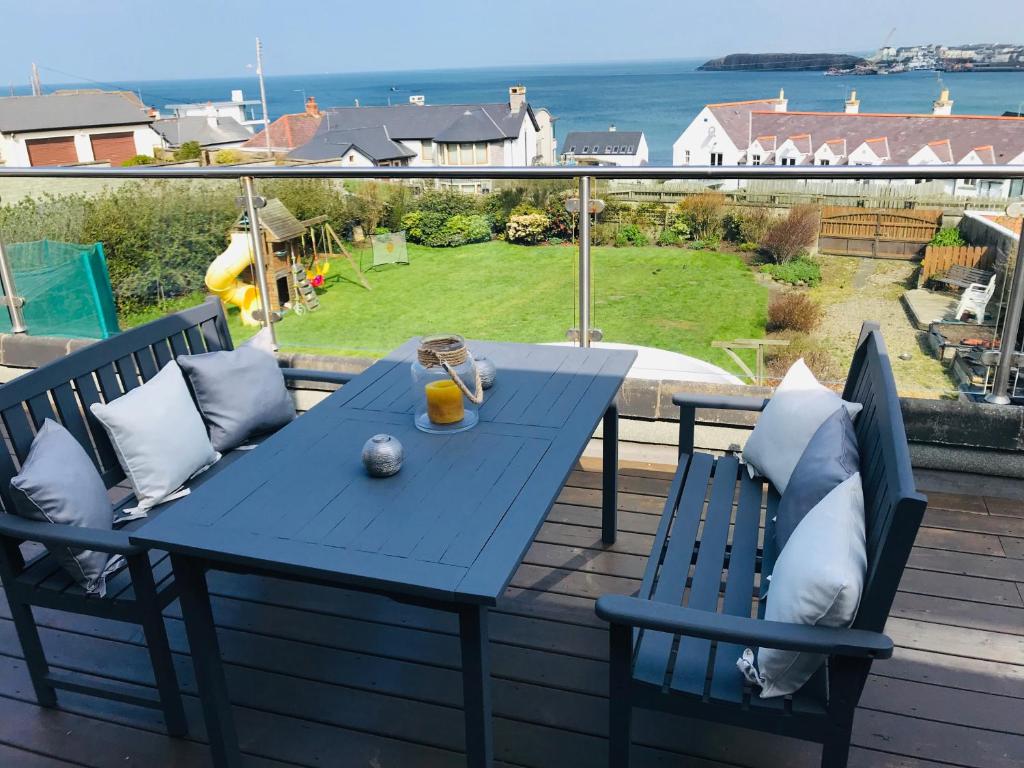 einen blauen Tisch und Stühle auf einer Terrasse mit Meerblick in der Unterkunft Hillrise B&B in Portrush