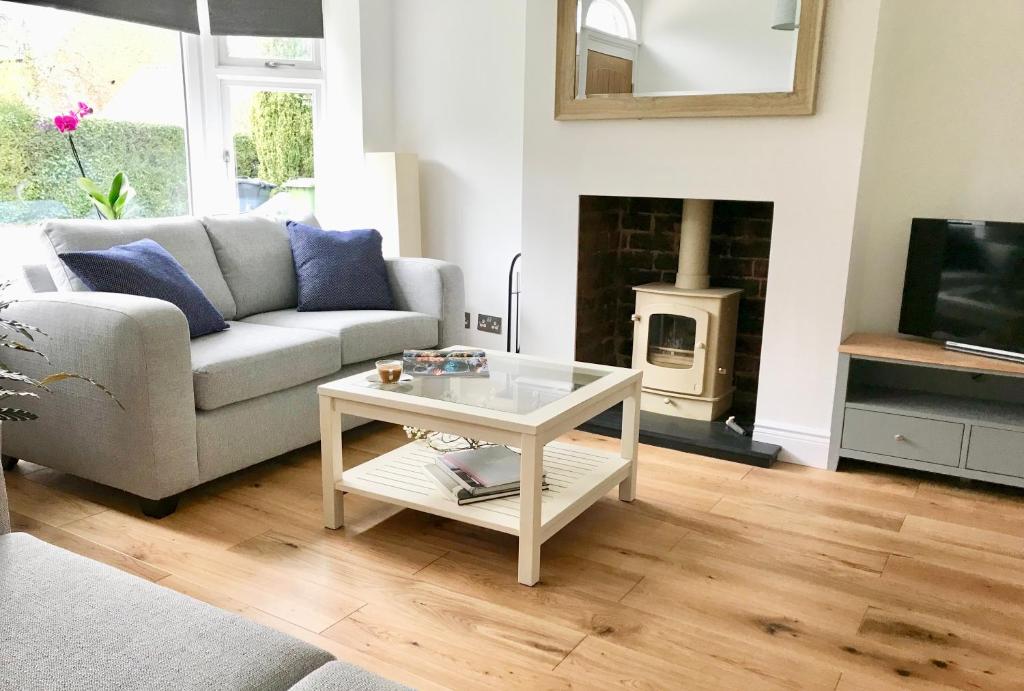 a living room with a couch and a table and a fireplace at Eden Cottage in Frodsham