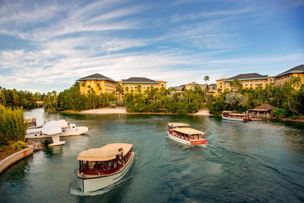 drie boten in een rivier voor gebouwen bij Universal's Loews Royal Pacific Resort in Orlando