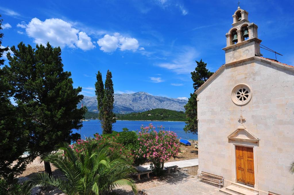 a church with a view of a lake and mountains at Vrnik Arts Club in Korčula