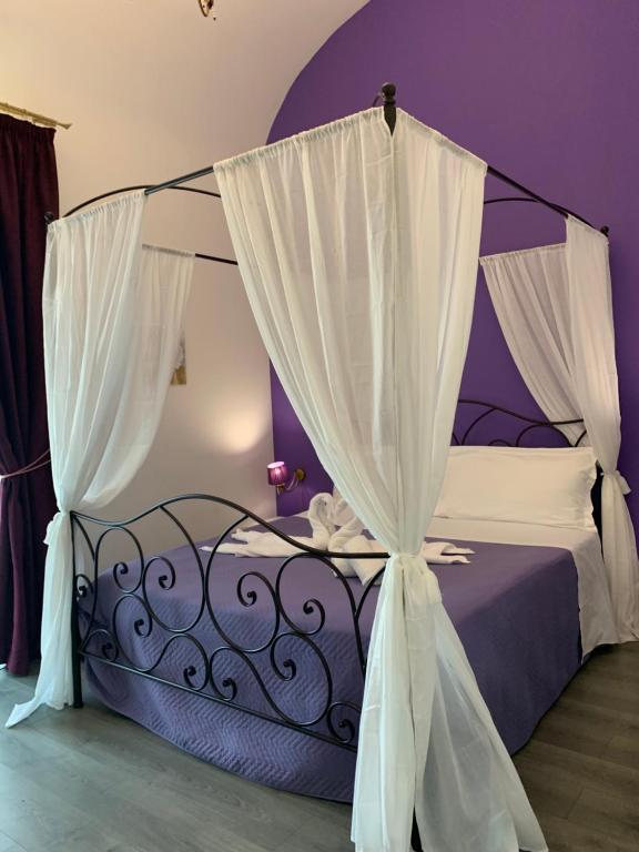 Dormitorio púrpura con cama con dosel y cortinas en Duca di Uzeda Bed & Breakfast Luxury and Style, en Catania