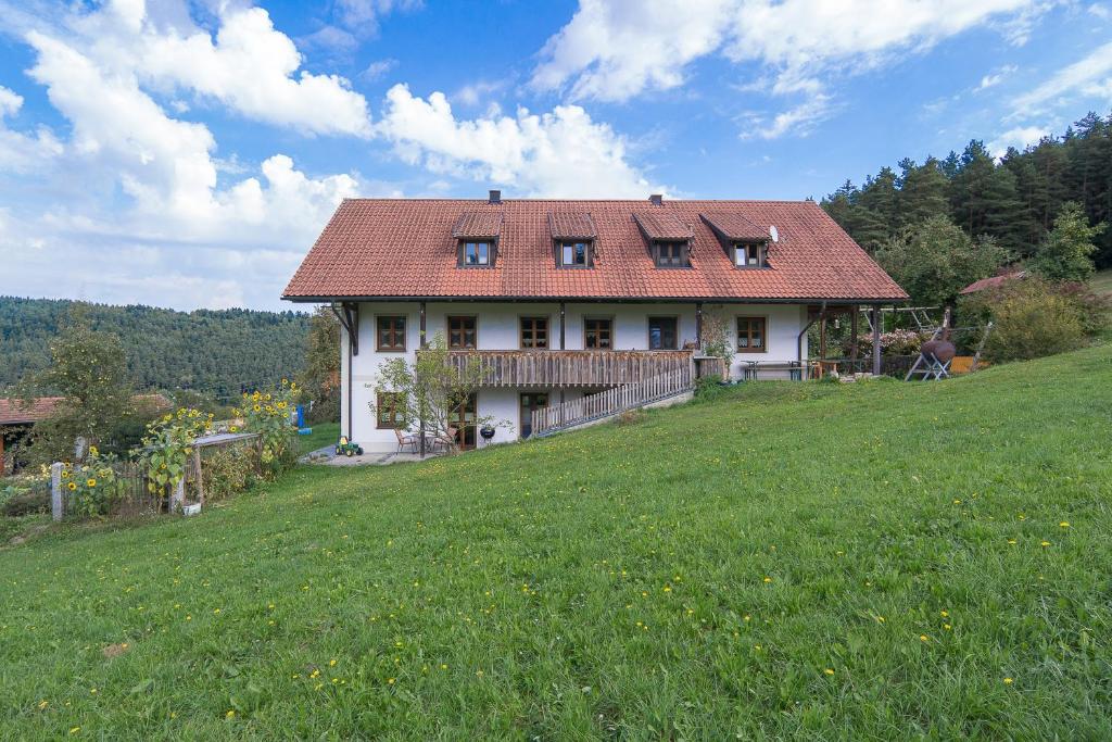 een wit huis met een rood dak op een heuvel bij Balsnhof in Chamerau