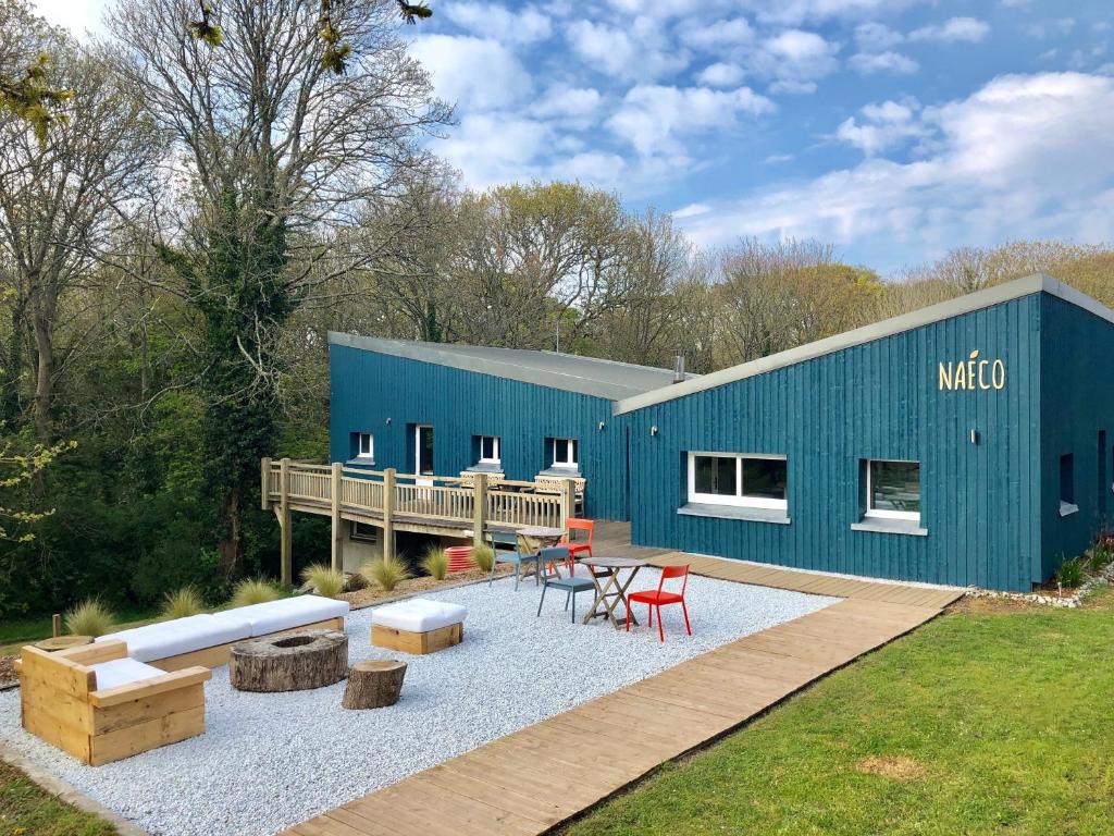 un bâtiment bleu avec une table et des chaises dans une cour dans l'établissement Camping Naéco Audierne, à Plouhinec