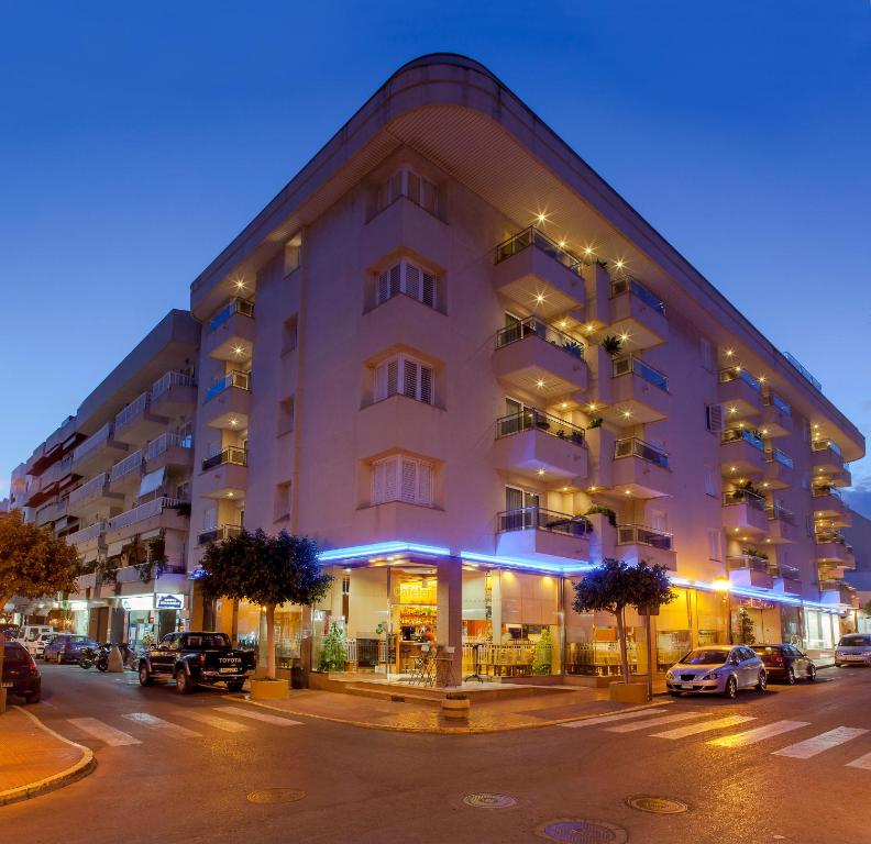 a large white building on a city street at night at Aparthotel Duquesa Playa in Santa Eularia des Riu
