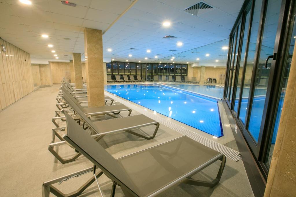 einen Pool mit Stühlen und einem Tisch in einem Gebäude in der Unterkunft Perun Hotel Sandanski in Sandanski