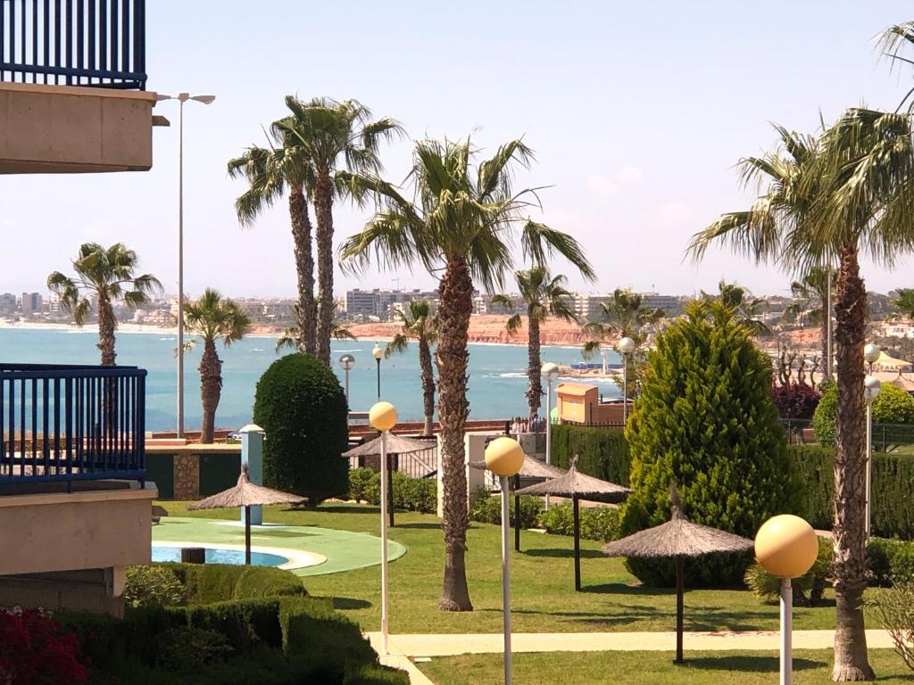 een uitzicht op een resort met palmbomen en parasols bij Cabo Roig - Blue Luxury Apartment in Cabo Roig