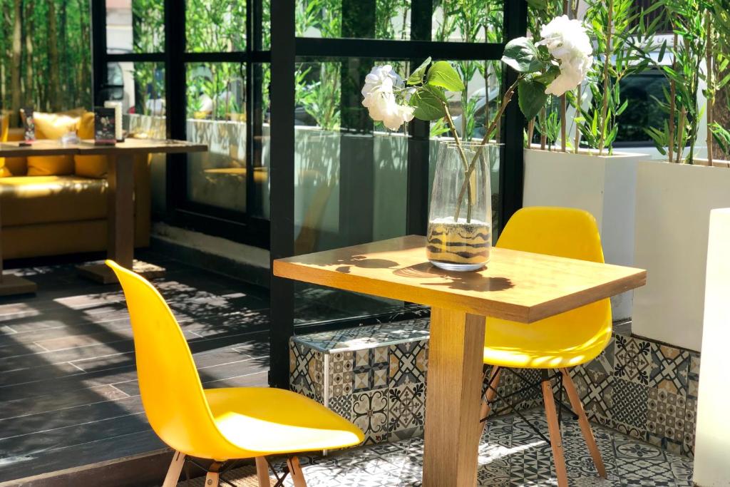 a table with yellow chairs and a vase with flowers on it at Suite Loc Suite & Spa in Casablanca