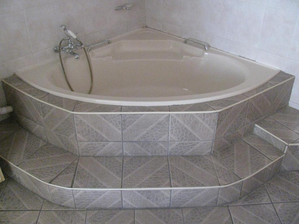a bath tub in a bathroom with a tile floor at Bruno Comfort Suites in Johannesburg