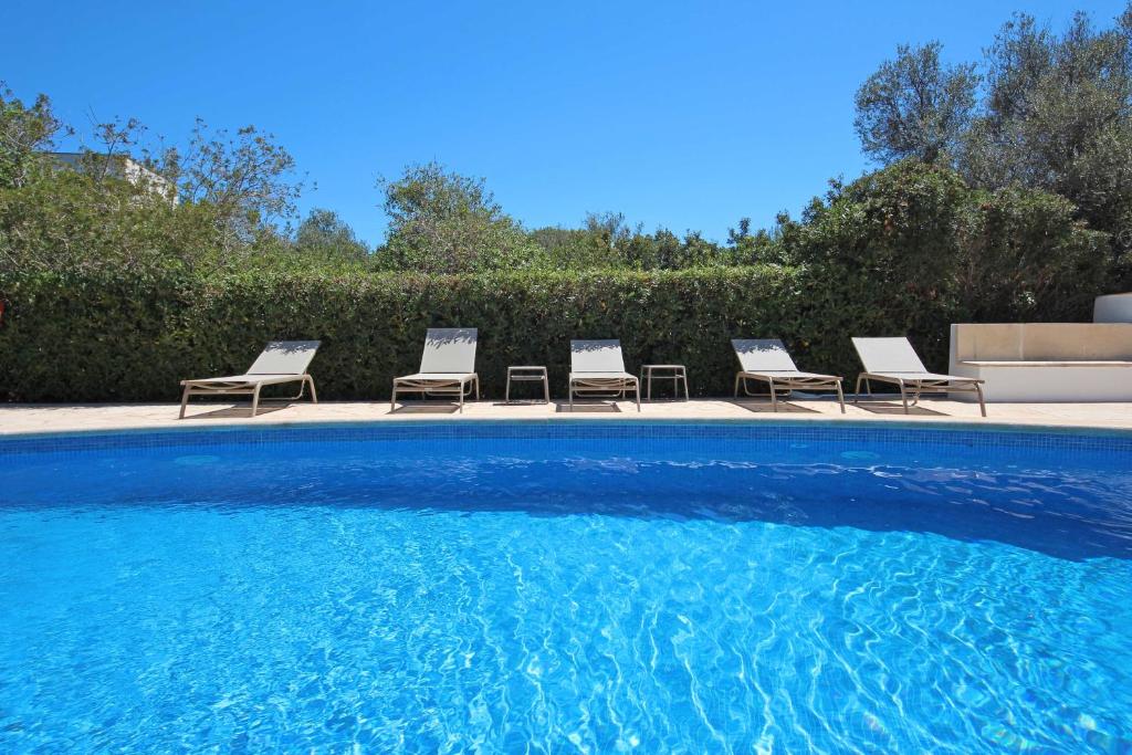 a group of chairs sitting next to a swimming pool at Aparthotel Niu d´Aus in Portopetro