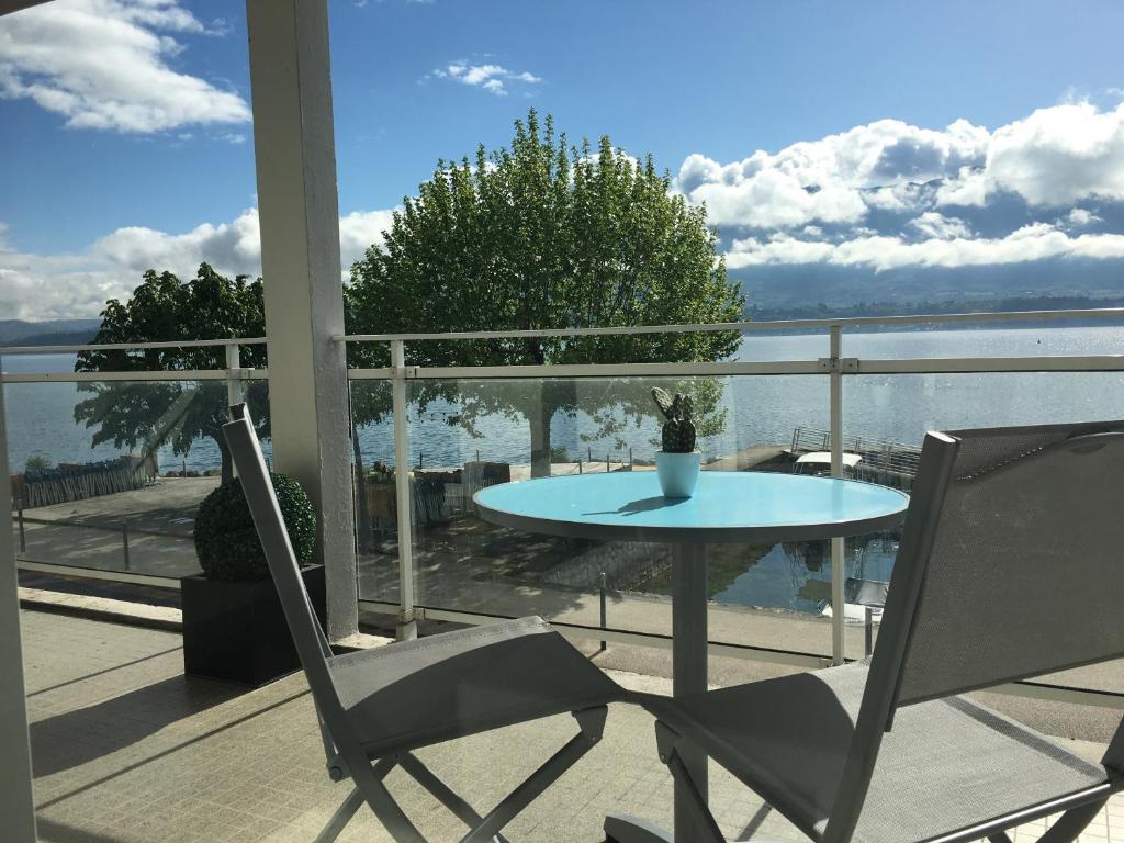 einen Tisch und Stühle auf einem Balkon mit Blick auf das Wasser in der Unterkunft Pieds dans l'eau au lac du Bourget in Le Bourget-du-Lac