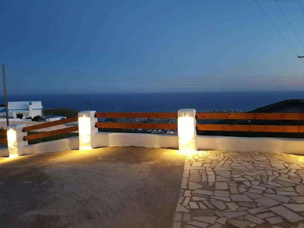 a bench sitting on the side of the ocean at night at Kampanelia Village Suites in Fira