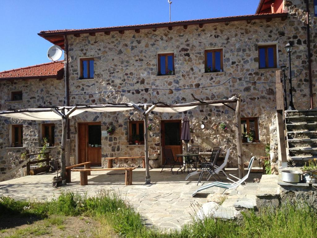 ein Steinhaus mit einem Picknicktisch und einem Sonnenschirm in der Unterkunft Azienda Agrituristica Risveglio Naturale in Varese Ligure