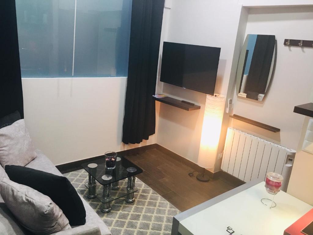 sala de estar con sofá y TV de pantalla plana en Apartamentos Deluxe Barajas en Madrid