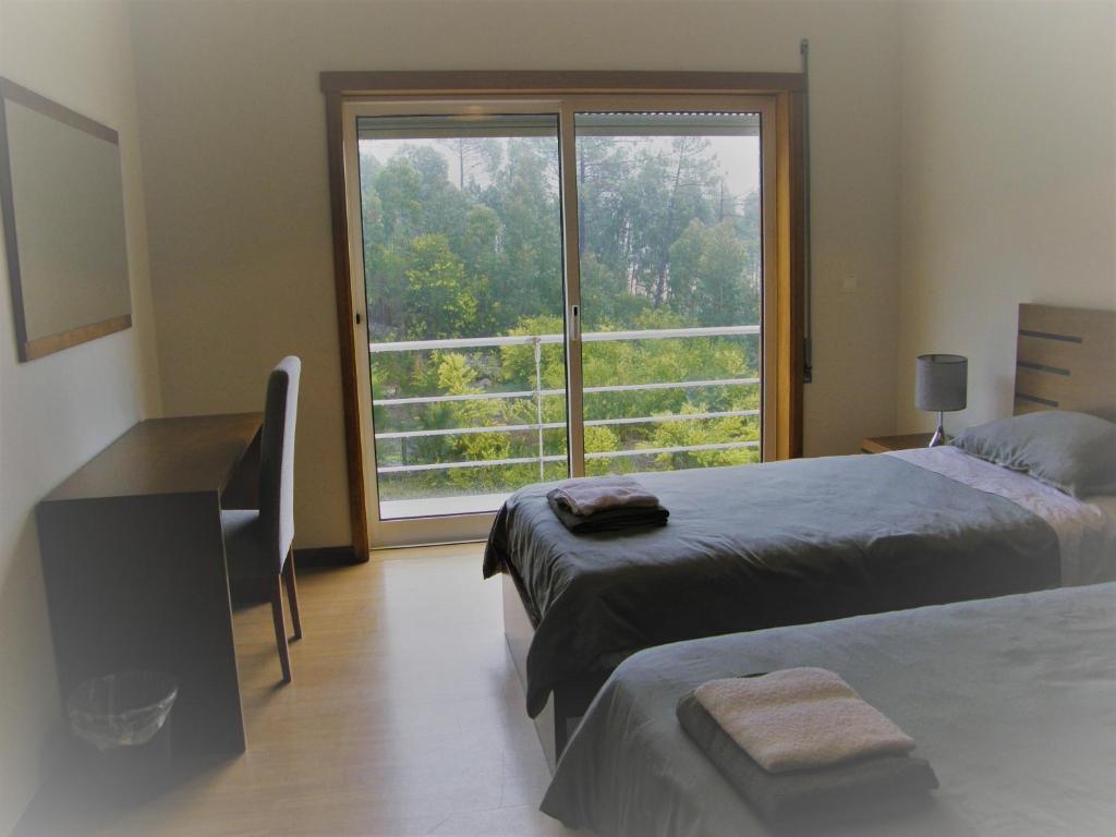 een slaapkamer met 2 bedden en een groot raam bij CasaJP in Viana do Castelo