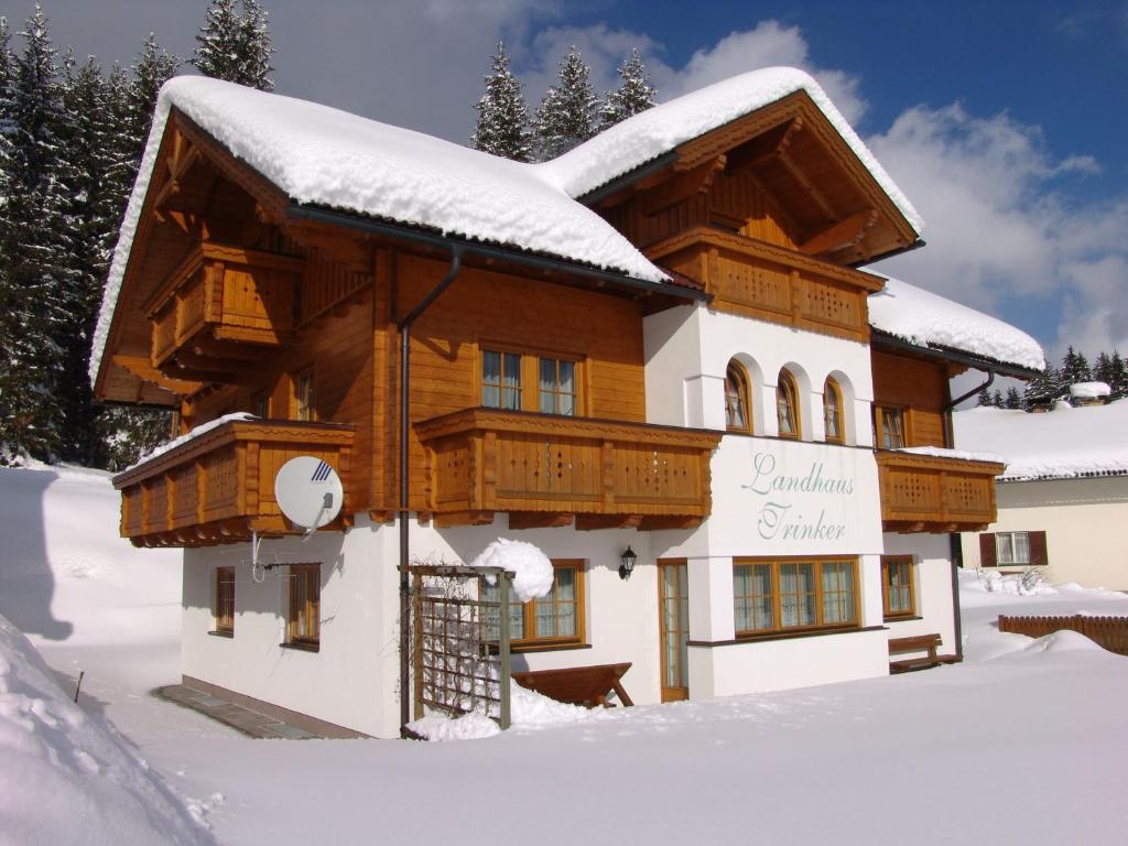 una cabaña de madera en la nieve con nieve en Landhaus Trinker, en Schladming