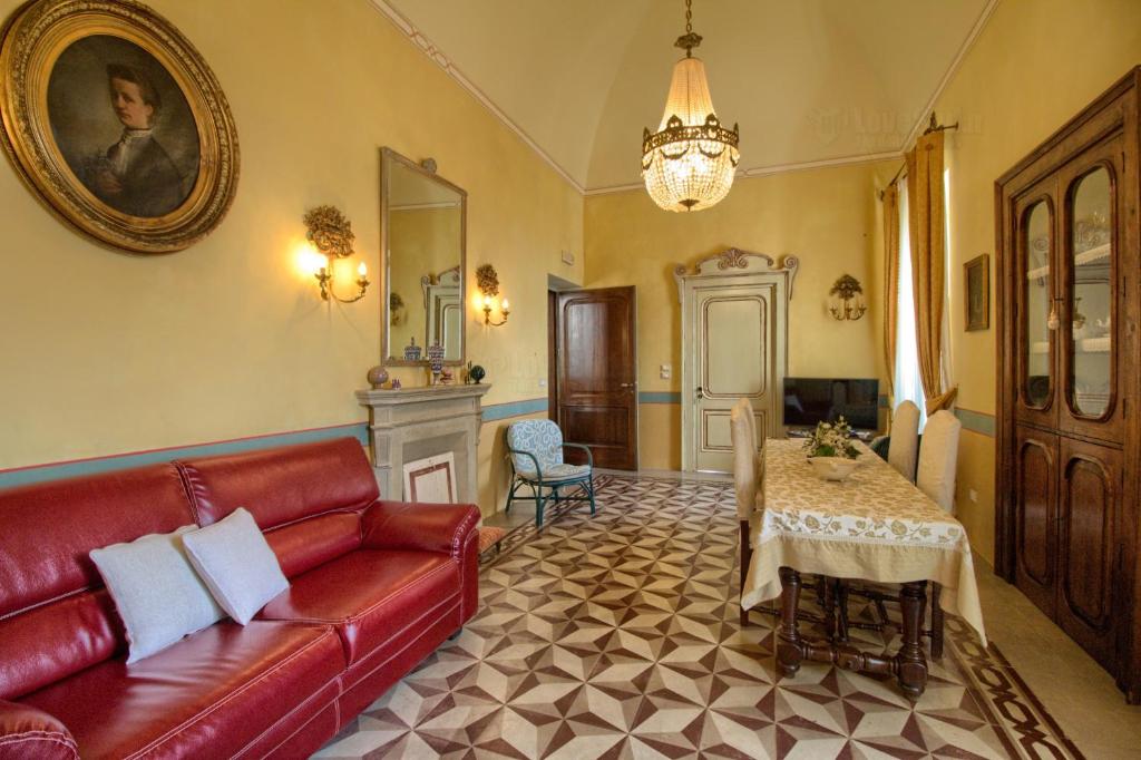 ガリアーノ・デル・カーポにあるB&B A Palazzoのリビングルーム(赤いソファ、テーブル付)