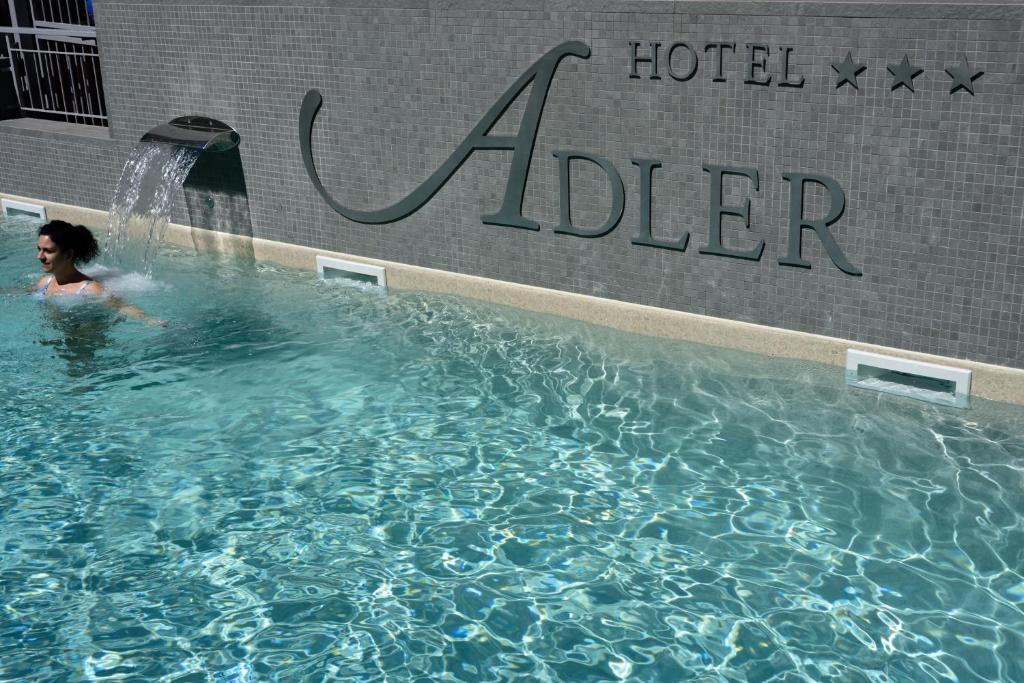 a woman in a swimming pool in a hotel adler at Hotel Adler in Alassio