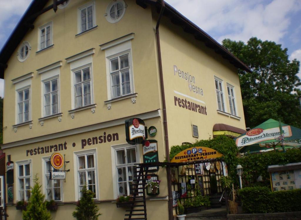 un grand bâtiment jaune avec des panneaux. dans l'établissement Pension a Restaurant VESNA - České Švýcarsko, à Srbská Kamenice